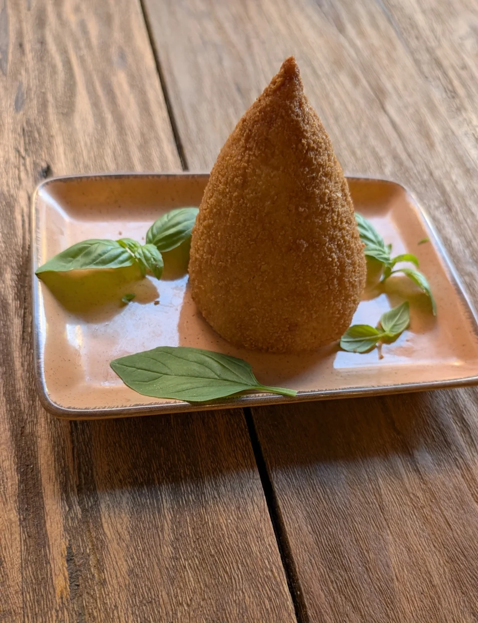 Goldbrauner Arancino auf einem Teller mit Salat