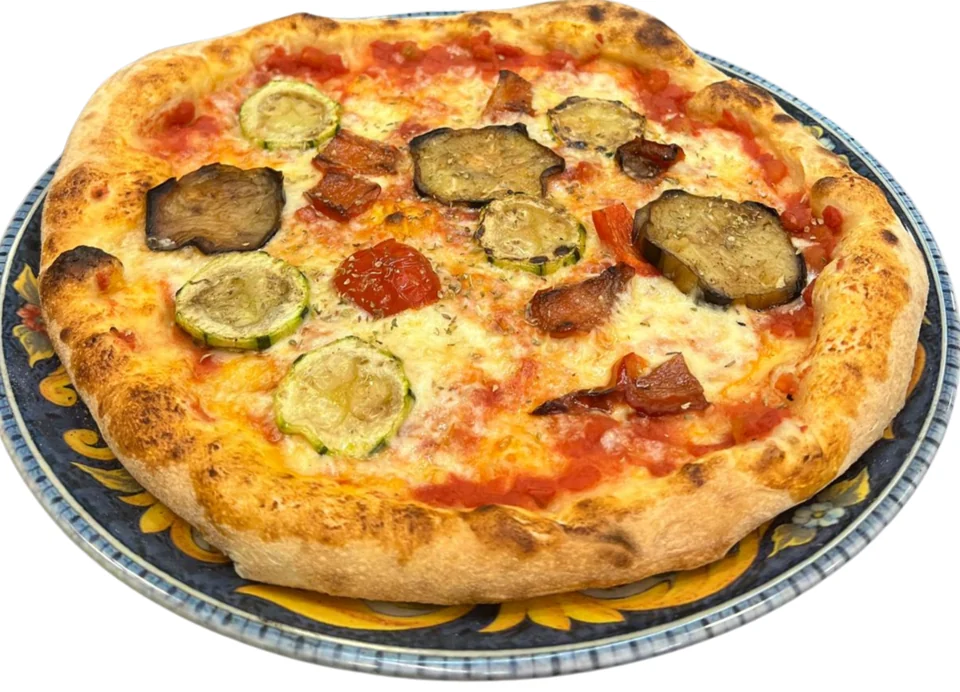 Pizza mit Zucchini und Auberginen auf einem bunten Teller