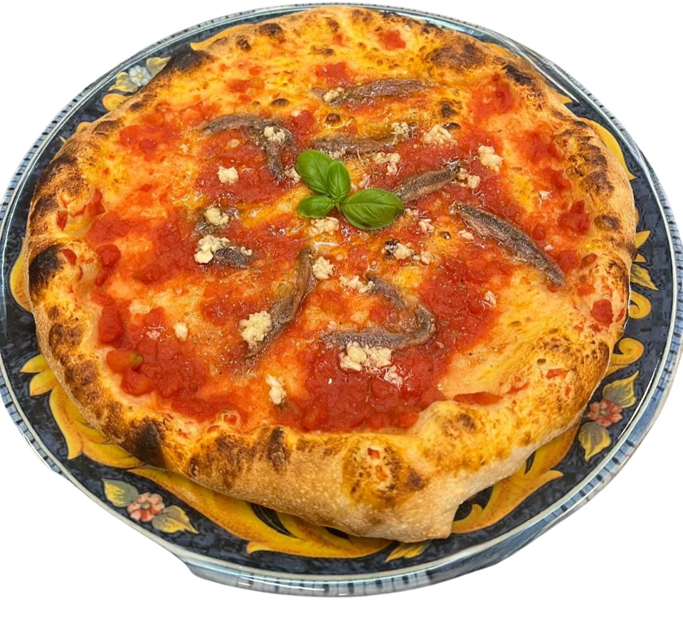 Pizza mit Tomatensauce und Sardellen auf einem gemusterten Teller